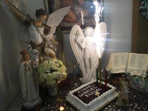 默主歌耶St Michael的一张桌子,上面有蛋糕,天使雕像和蜡烛