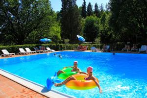 锡耶纳锡耶纳科勒维德露营酒店的两人在配有充气设施的游泳池玩耍