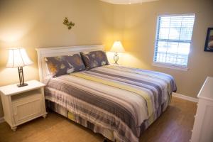 True BluePawleys Island Vacation Rentals llc的一间卧室配有一张床、两盏灯和一个窗户。