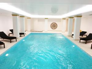 雅典迪奥森尼亚宫酒店的一个带椅子和桌子的房间的游泳池