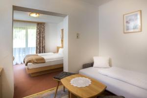 弗拉塔赫Alpenhotel Badmeister的酒店客房设有两张床和一张桌子。