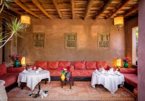 马拉喀什简尼莱拉住宿加早餐旅馆的客厅配有红色的沙发和2张桌子