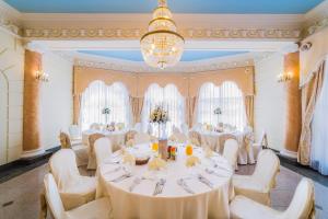 雅罗斯瓦夫雅罗斯瓦夫酒店的宴会厅配有白色的桌椅和吊灯。