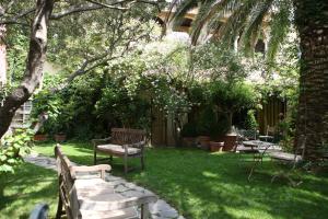 尼姆秘密花园酒店的花园设有长椅和桌子,树木繁茂