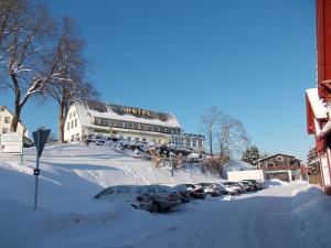 圣安德里斯伯格Berghotel Glockenberg的一条雪覆盖的街道,在建筑物前停放汽车