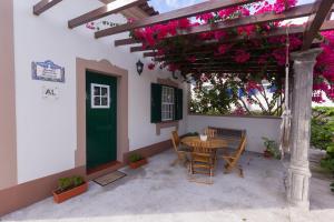 FeteiraCasa das Vinhas的庭院配有桌椅和粉红色的鲜花。