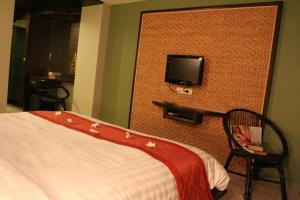 拉迈Lamoon Lamai Residence & Guesthouse的一间卧室配有一张床,墙上配有电视