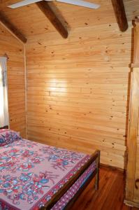 美洲花园Las Cabanas的卧室配有一张床铺,位于带木墙的房间内