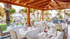 普拉亚布兰卡Hipotels Natura Palace Adults Only的餐厅拥有白色的桌椅和棕榈树