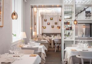 乌普萨拉安娜别墅酒店的餐厅配有白色的桌椅和镜子