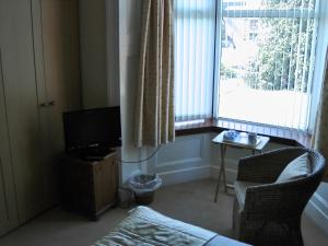 戴斯Beeches Guest House的一间带电视、椅子和窗户的客厅