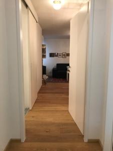 维也纳毕蔓仁塔尔1号公寓 的走廊通往带白色墙壁和木地板的客厅