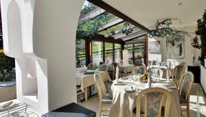 达沃斯Residenz Larix Apartments的餐厅设有白色的桌椅和窗户。