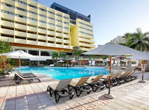 圣多明各Dominican Fiesta Hotel的酒店前方的游泳池配有椅子和遮阳伞