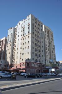 科威特豪维里1号特雷斯服务公寓的一座白色的大建筑,汽车停在停车场