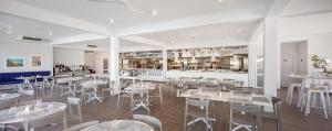 米欧纳Gava Waterman Milna Resort – All Inclusive的一间带白色桌椅的餐厅和一间厨房