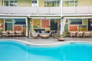 洛杉矶Avalon Hotel Beverly Hills, a Member of Design Hotels的酒店前方设有桌椅的游泳池