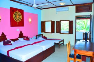 阿努拉德普勒The Triangle Hotel的一间卧室设有两张床、一张桌子和粉红色的墙壁