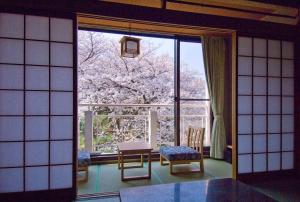 奈良米卡萨酒店 的客房设有大窗户、桌子和椅子。