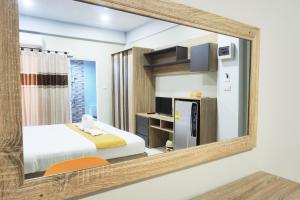 坤敬Supreme Place SHA Plus的镜子反射着一间卧室,配有一张床和冰箱