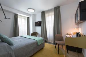 塞拉伦加达尔巴Villaggio Narrante - Le Case dei Conti Mirafiore的酒店客房设有一张床、一张书桌和窗户。