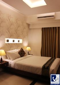 达卡安克雷奇酒店的一间卧室配有一张床和两盏灯及窗帘