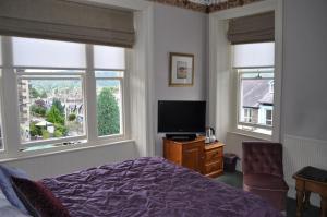 鲍内斯温德米尔The Westbourne的一间卧室设有一张床、一台电视和两个窗户。