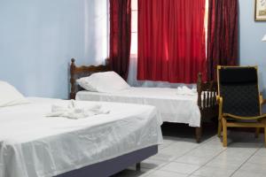 马那瓜Hotel Valerie的客房设有两张床和一个带红色窗帘的窗户。