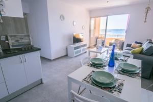 大塔拉哈尔Apartamentos Ocean View的厨房以及带盘子桌的客厅。