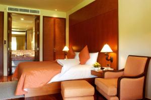 波湾普吉观澜湖岛高尔夫度假村 - SHA Extra Plus的一间卧室配有一张大床和一把椅子