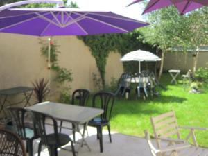 帕雷·勒·毛尼尔圣路易斯住宿加早餐旅馆的一组桌子和椅子,配有紫色雨伞