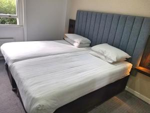 伦敦花园府酒店的一张带白色床单和枕头的床