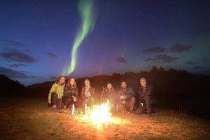 特罗姆瑟特罗姆瑟活动旅舍的一群人坐在火炉旁的北极光下