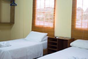 马那瓜Hotel Valerie的一间卧室设有两张床和两个百叶窗