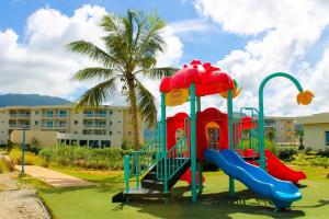 AltagraciaLD Suites Punta Playa的棕榈树建筑前的游乐场