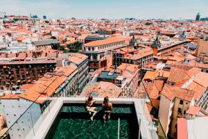 马德里马德里迪尔酒店的两名妇女坐在一座俯瞰城市的建筑的边缘