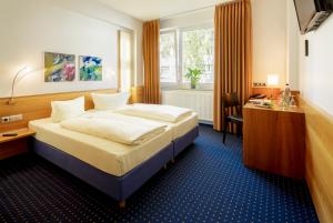 科隆MesseHotel Köln-Deutz的配有一张床和一张书桌的酒店客房