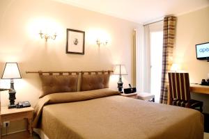 巴黎阿尔贝巴士底酒店的一间卧室配有一张床、两盏灯和一台电视。