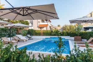 帕科坦Villa Zdenka的一个带遮阳伞和椅子的游泳池以及一个游泳池