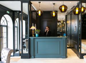 巴黎Hotel de Neuville Arc de Triomphe的站在餐厅蓝色酒吧的女人