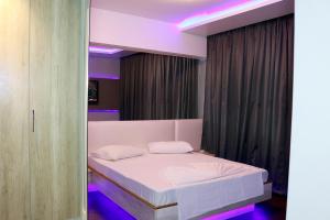 尼泰罗伊尼泰罗伊培亚格兰德酒店的一间卧室配有一张白色床和紫色灯