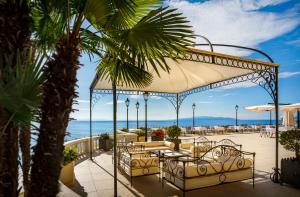 奥帕提亚Hotel Kvarner - Liburnia的一个带桌椅的庭院和大海