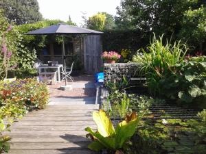 埃尔默洛Bed and Breakfast de Verwennerij的花园设有木甲板、桌子和遮阳伞