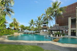 甘地达萨Candi Beach Resort & Spa的棕榈树建筑前的游泳池
