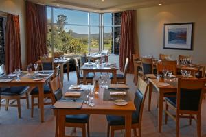 福克斯冰川荣誉福克斯冰河 - 蒂维希卡精品酒店的餐厅设有木桌、椅子和窗户。