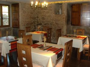 卡马里尼亚斯A Casa da Gandara的一间设有白色桌椅和石墙的餐厅