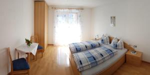 瓦尔道拉Appartements Oberleiter的一间卧室配有一张床、一张桌子和一个窗户。