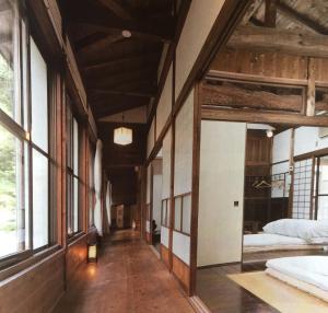 南木曾町Takimi Onsen Inn that only accepts one group per day的带两张床的客房和窗户的走廊