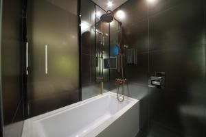 首尔天玺开浦酒店的带浴缸和玻璃淋浴间的浴室。