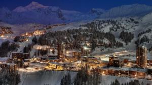 艾姆拉普拉涅Plagne AIME 2000 Ski Apartments的夜雪中点燃的城市